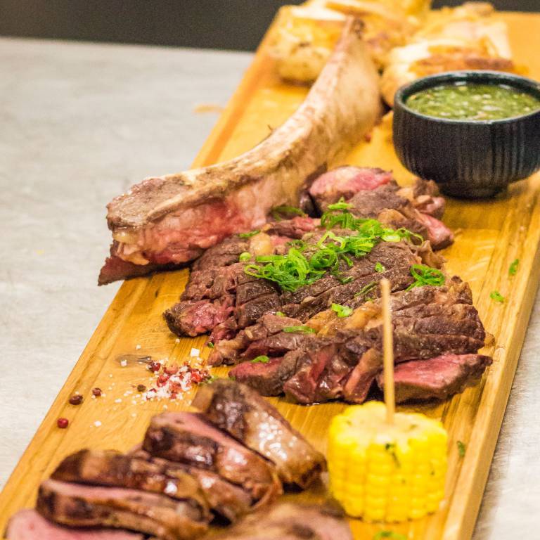 BBQ Brett mit aufgeschnittenem Fleisch und Mais